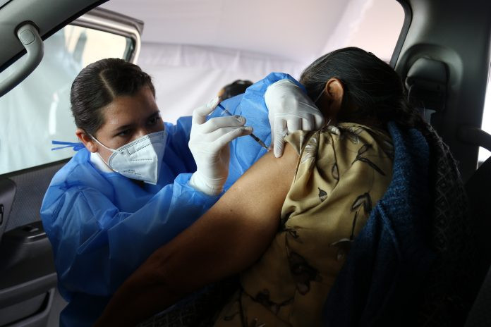 Mujer vacunando a adulta mayor en unidad vehicular