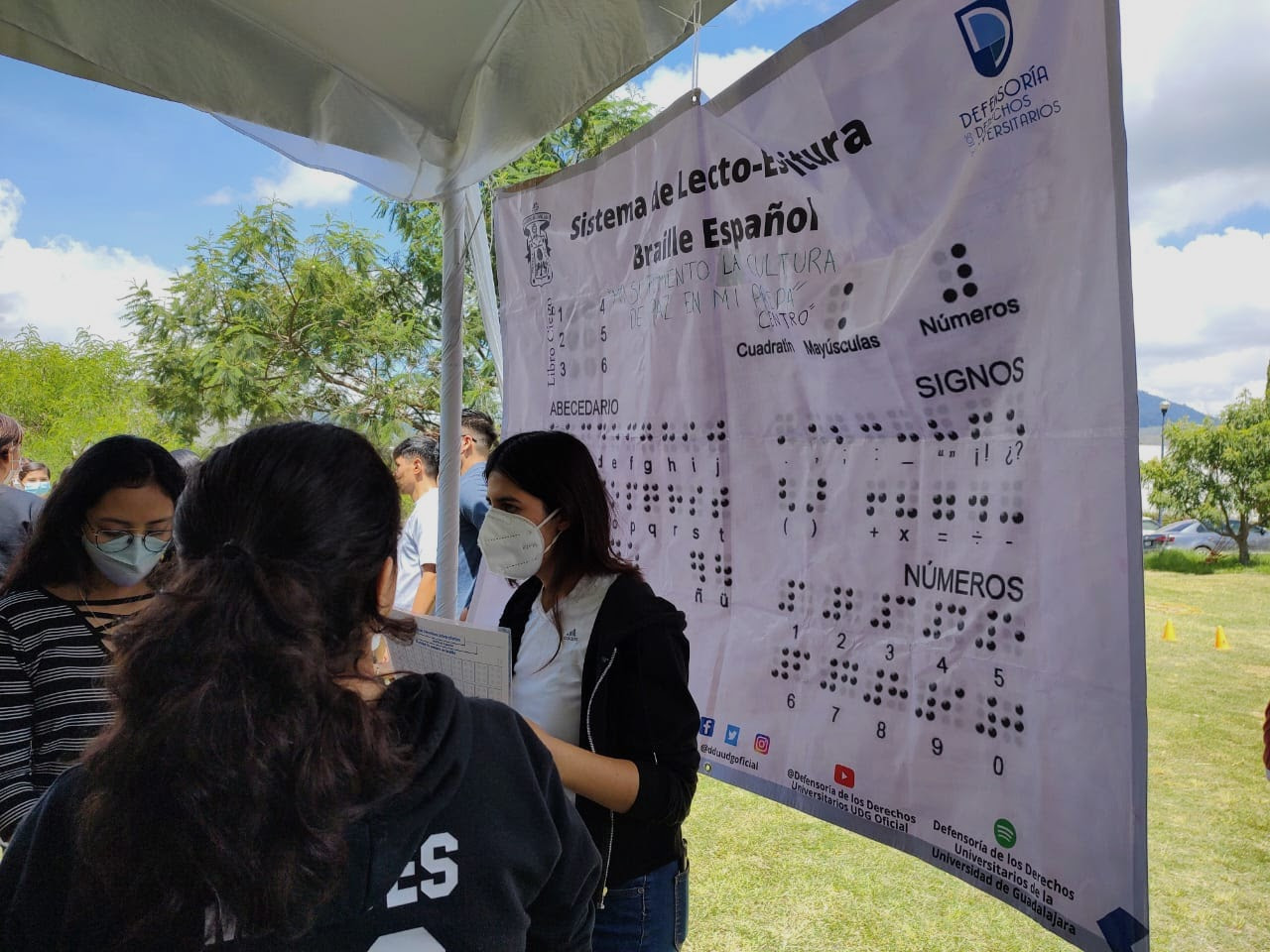 Estudiantes partcipando en actividad de la DDU, con un abecedario en braile de fondo